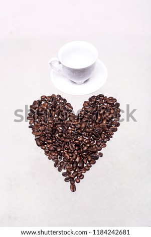 Coffee beans lined heart on a white background.With a white cup for coffee