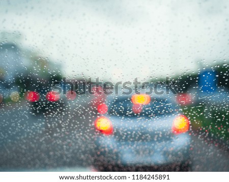 Soft focus rain drops and blurred light car on the road in rainy day.