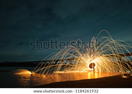The Fire Burning steel wool spinned in the lake near the bridge at the Pa Sak Jolasid Dam Showers of glowing sparks from spinning steel wool very nice and beautiful at night time at Lopburi, Thailand