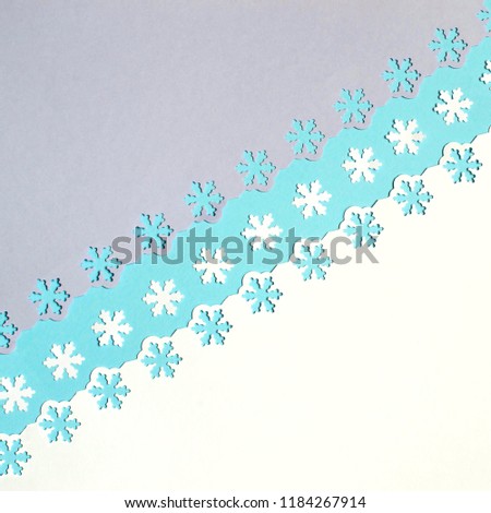 Colorful festive background of three colors of paper with snowflakes, carved with figured punch. Flat design for winter, Christmas or New Year cards. Minimal paper art style