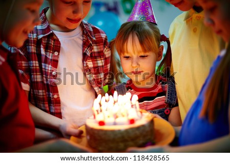 Group of adorable kids looking at birthday cake with candles