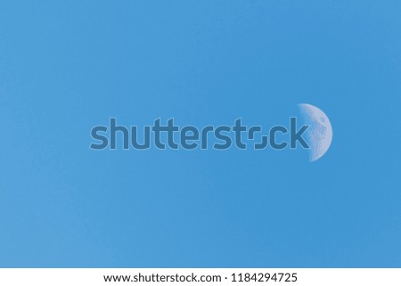Picture of a half moon on a clear blue sky middle right