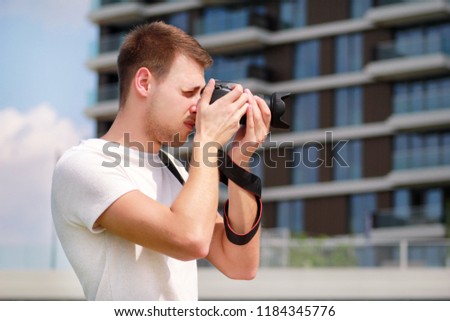 Professional photographer examining scenery and taking pictures of environment, architecture, urban elements, river, old green bridge. Tourist and traveler is making landscape photography with camera.