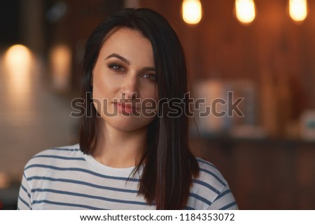 Pretty face girl looking forward over a modern interior background with lights. Cute woman portrait, close-up.