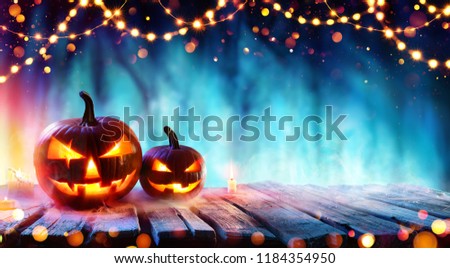 Halloween Party - Pumpkins And String Lights On Table In Dark Forest
