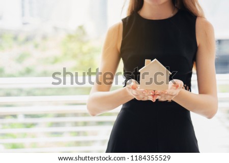 Close up female hand holding model house. Planning home trading deal. Investment is online to find customers who are interested buying and renting. Team of consultants available assist in selection.