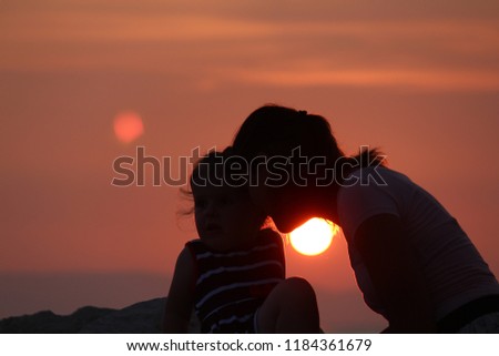 A young mother and daughter in the background of sunset sea