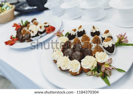 white plates with chocolate cakes and truffles, decorated with fresh flowers, dessert table at the Banquet at the wedding