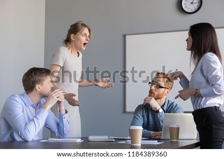 Business women colleagues disputing arguing at corporate office meeting, mad angry shocked female employee disagree with coworker blaming for bad work, conflict and rivalry at workplace concept Royalty-Free Stock Photo #1184389360