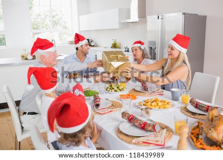 Festive family exchanging gifts at christmas at the dinner table