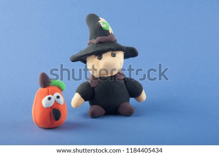 Halloween toys on blue background. Gnome and pumpkin made of modelling dough