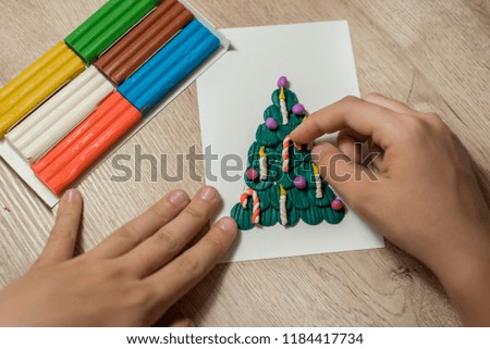 Christmas children's craft of plasticine. a green Christmas tree with balls and toys. The concept of a New Year's holiday with gifts