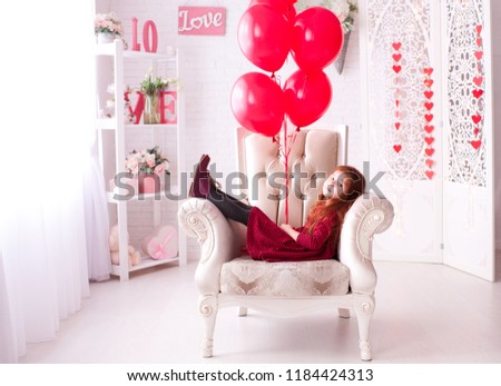 Smiling baby girl 3-4 year old holding red balloons in room. Birthday party. Childhood. 