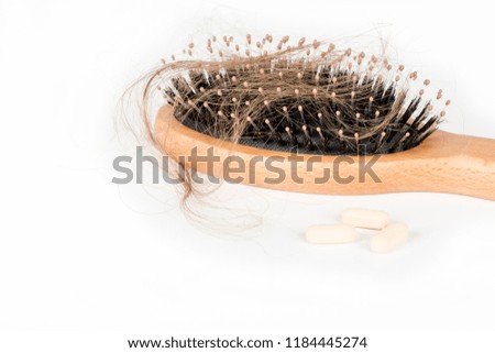 Wood hairbrush on white background. Close-up with long brown hair. Hair loss problem. Health care concept