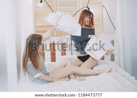 Two beautiful girls on a big white bed