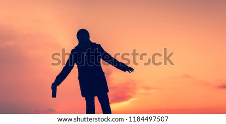 A drunk young man is walking staggering down the street. Silhouette of a Drunkard. A guy with a bottle of alcohol in his hand.