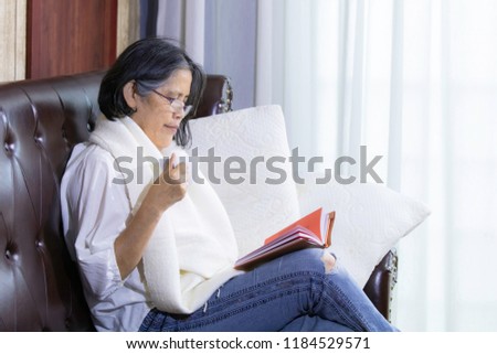 Old age lifestyle, senior woman with blonde hair stay at home sit on the sofa near window read book with relax /lifestyle concept
