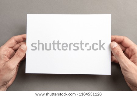 Mens hands holding empty white letterhead on light gray background. Blank paper mock-up