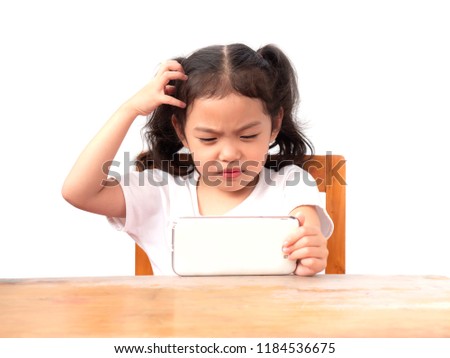 Little cute girl sitting on chair and use hand scratching a head. While she watching smartphone with seriously on white backdrop. If children watches a phone too much they may have ADHD.