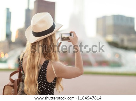 Tourist girl taking picture of buckingham fountain chicago and the skyline on the background
