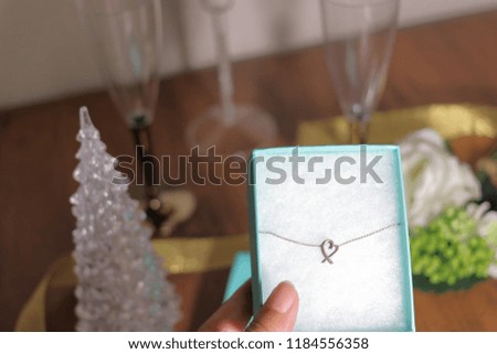Present of heart necklace held in hand and Christmas table coordination