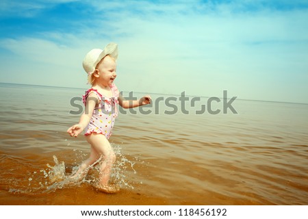 happy small girl running on the beach