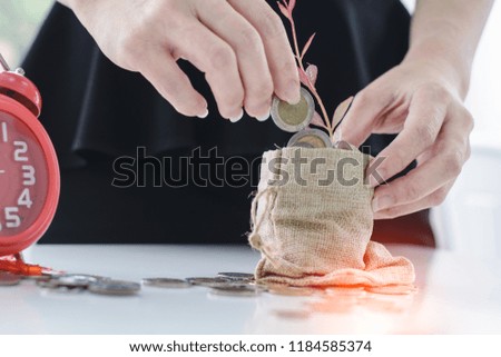 Human hand is putting coin to the bag with clock  for saving money concept
