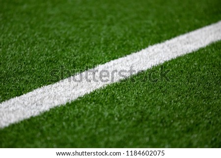 Close up on a white line in artificial green turf, on a soccer and football field, in a sports background