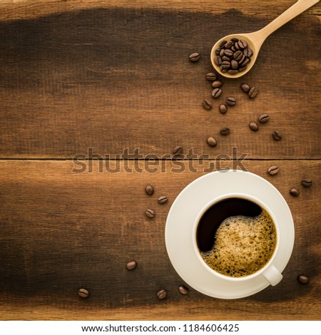 Top view of coffee in white cup And coffee beans with wooden spoon and copy space on wooden background.