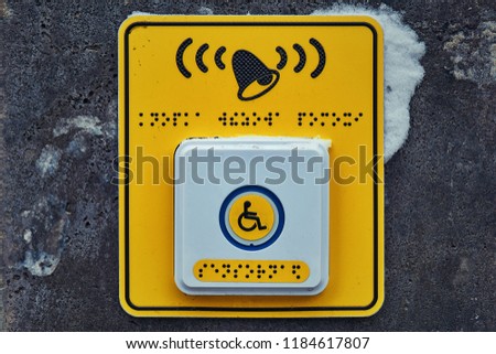 Button on a yellow background for the disabled in front of a high staircase with Braille