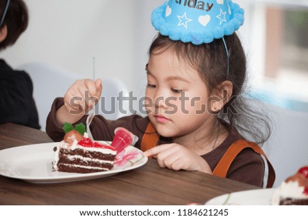 Little girl with hat eating birthday cake