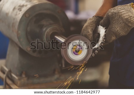 Closeup angle Grinder hand holding and Grinding the spare parts of metal gear in lathe metalworking factory, industry concept