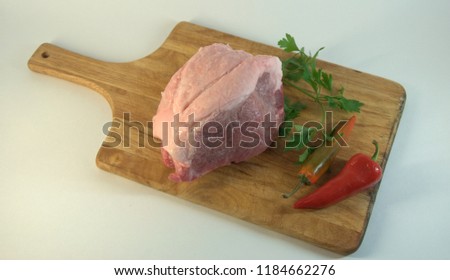 Fresh fillet of pork, on a chopping board with a stem of parsley and red and green hot pepper. A picture on a white background close-up.
