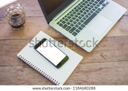 smartphone with laptop on wooden table and working in the park. subject is blurred.