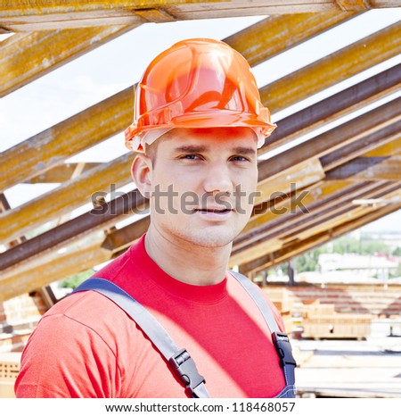 Young builder on a background of metal roof trusses