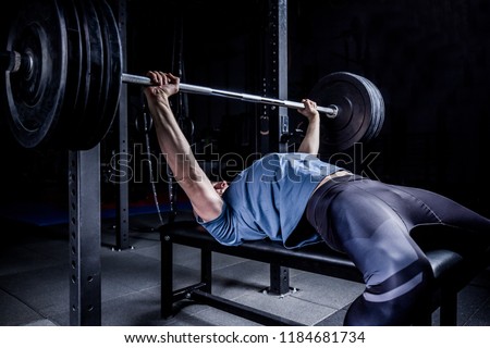 Athletic Man In Gym Exercising On The Barbell Bench Press.  Royalty-Free Stock Photo #1184681734