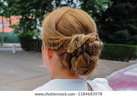 Rear view of a female hairstyle with a chignon, model with fair hair and middle bun