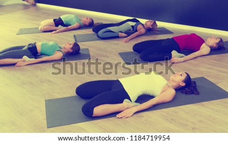 Young women exercising yoga poses in fitness center