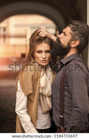 One beautiful stylish couple of young woman and man with long black beard standing embracing close to each other outdoor in autumn street near arch, vertical picture