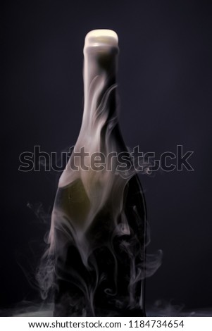 Closeup view of one new open full champagme wive sweet or dry drink green glass bottle with beautiful white smoke for celebration christmas or new year in studio on blue background, vertical picture