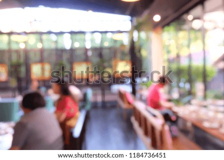 Blurred people are sitting on table in cafe or restaurant.