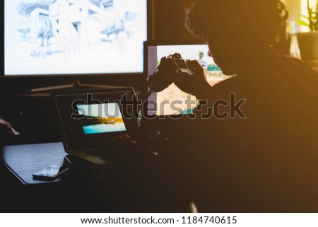 young male photographer editing made photos at home studio on laptop and desktop computer