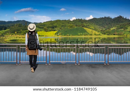 Asian female tourists, She wears casual style Japanese.with simple black backpack and camera with lens behind looking landscape view of autumn.