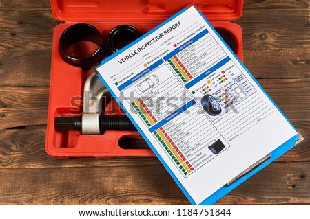Vehicle vehicle inspection report form against the background of automotive tools on the wooden background. Close up. Royalty-Free Stock Photo #1184751844