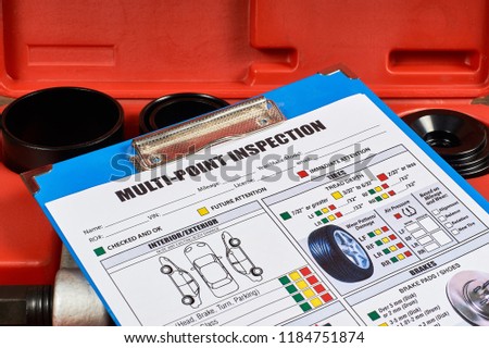Vehicle multi-point inspection form against the background of automotive tools. Close up. Royalty-Free Stock Photo #1184751874