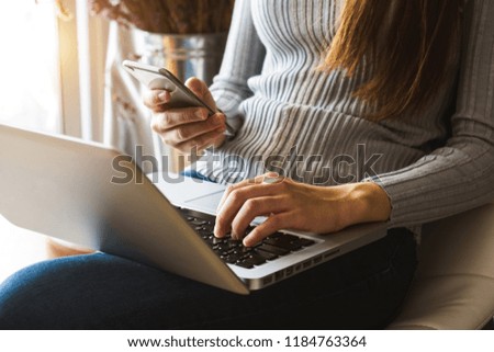 Woman using smart phone for mobile payments online shopping,omni channel,sitting on table,graphics interface screen in morning light