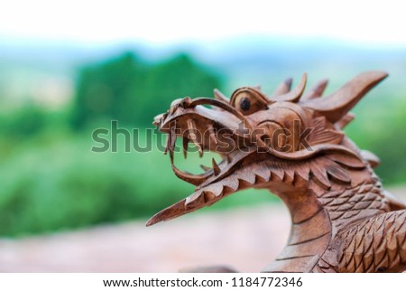 Wooden dragon face in a perfect blurry landscape background