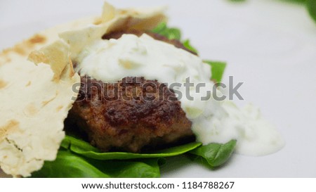 Mediterranean Pita Burger with Tzatziki Sauce on a White Plate on a White Background