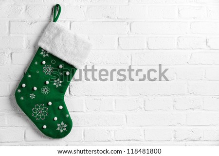Green Christmas sock hanging on white brick wall