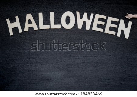 Wood letter "HALLOWEEN" and little dolls hand on black wood background. Holiday season. Party. Can be use for advertising, banner, brochure, web. Free space for text.